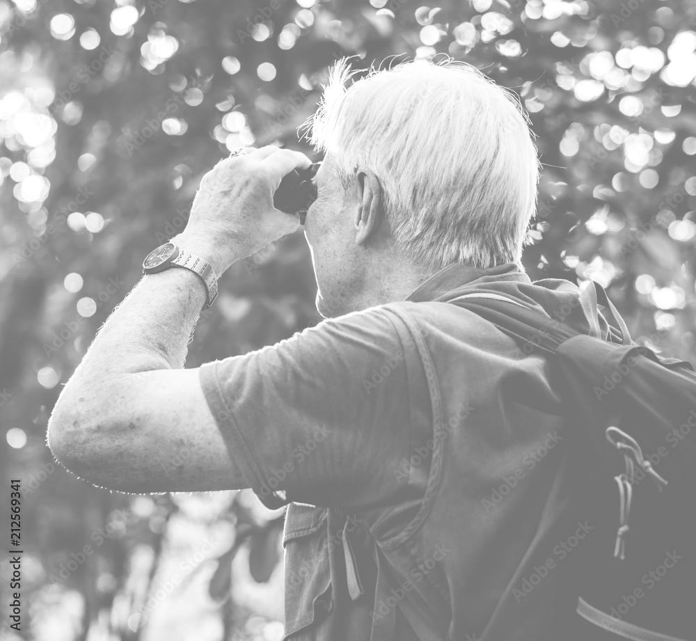 Mature man watching birds through binoculars