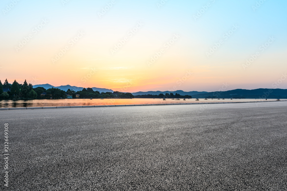 Empty asphalt road and hills silhouette at sunset