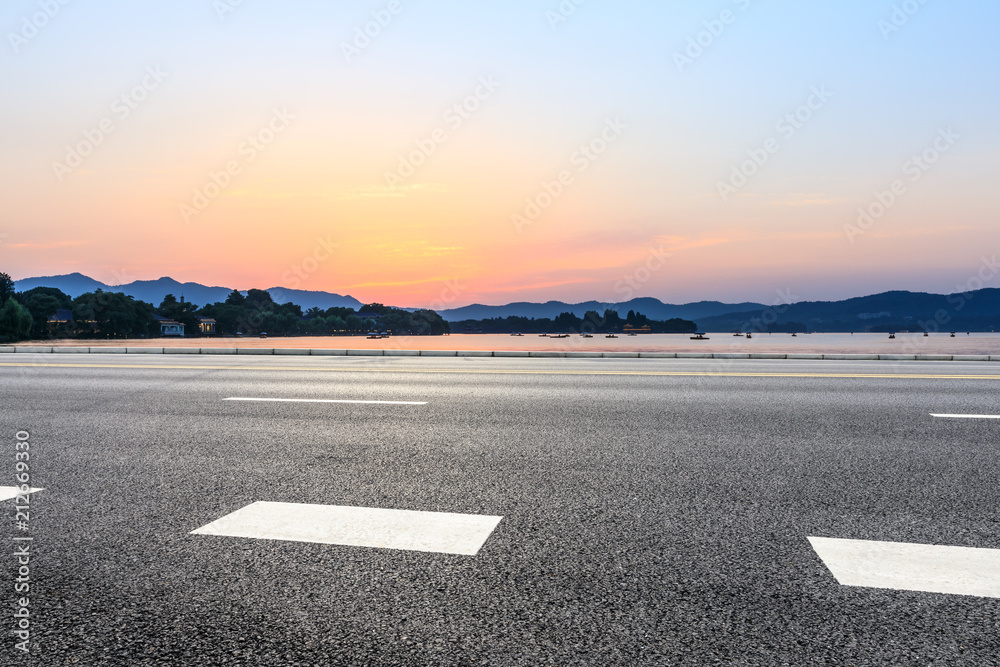 Empty asphalt road and hills silhouette at sunset