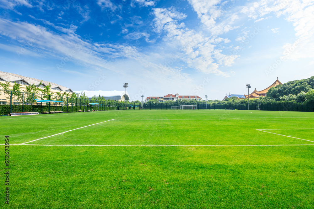 Green football field under blue sky background