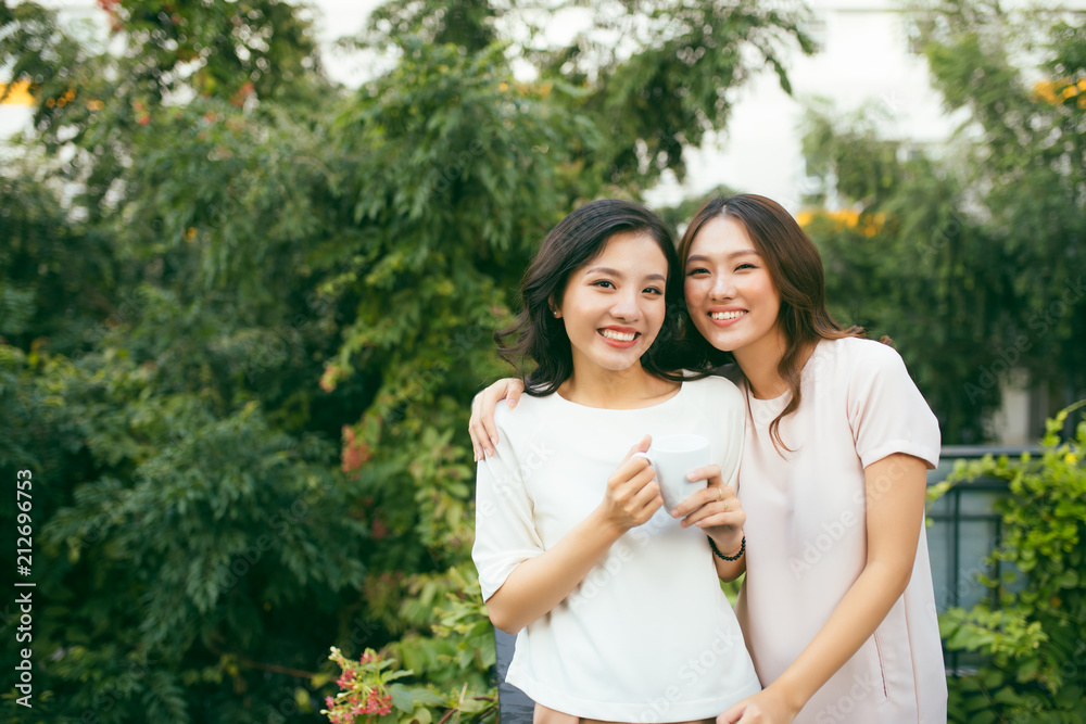 两个穿着得体的年轻美女在户外喝咖啡聊天