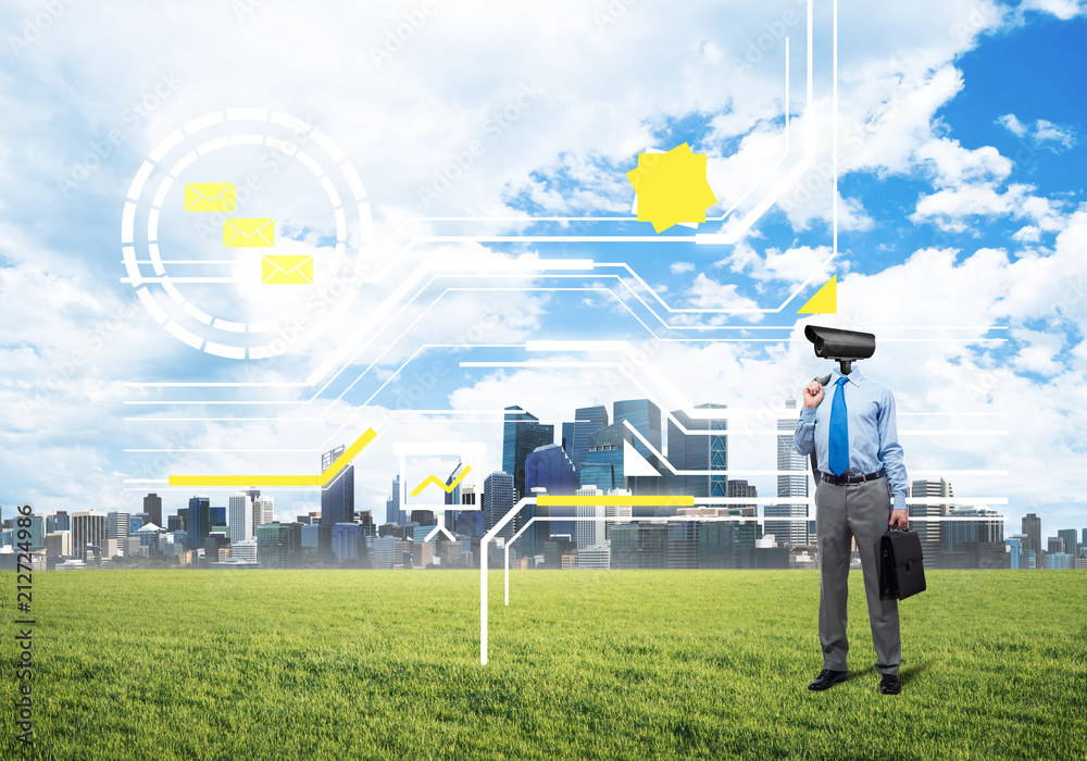 Camera headed man standing on green grass against modern cityscape