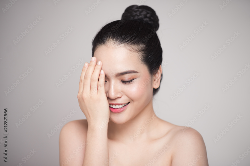 Happy smiling beautiful asian woman touching her face.