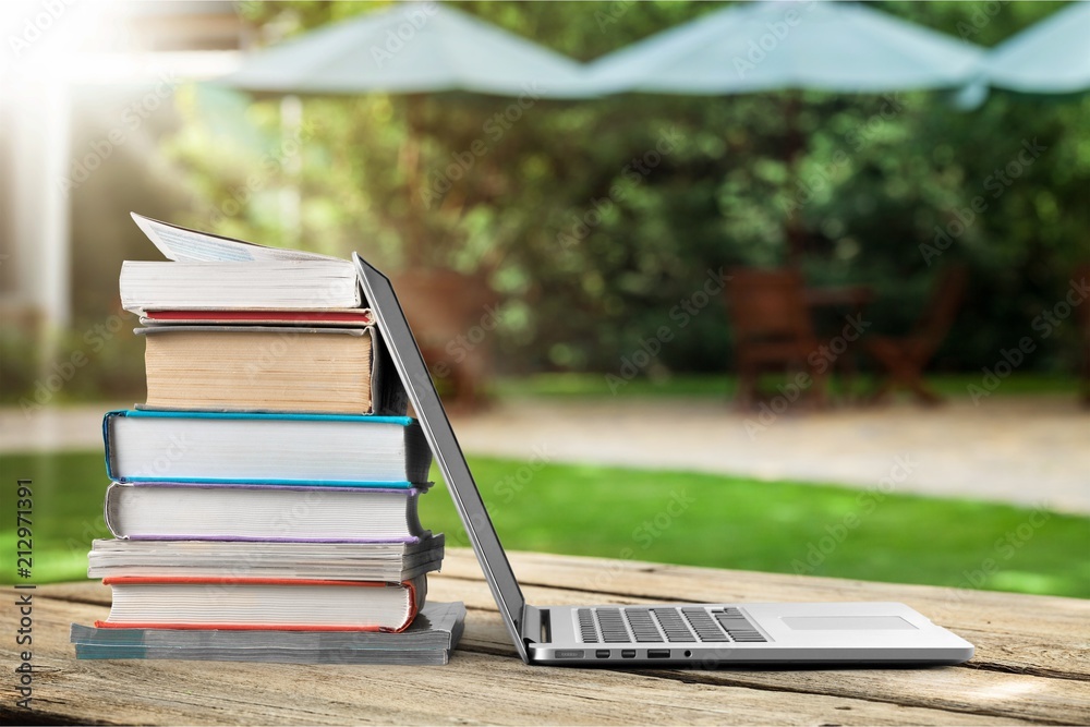 Stack of books with laptop on table