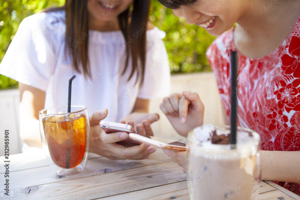 ドリンクを飲みながら、スマートフォンを操作している女性たち。