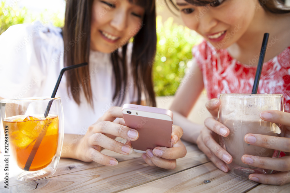 ドリンクを飲みながら、スマートフォンを操作している女性たち。