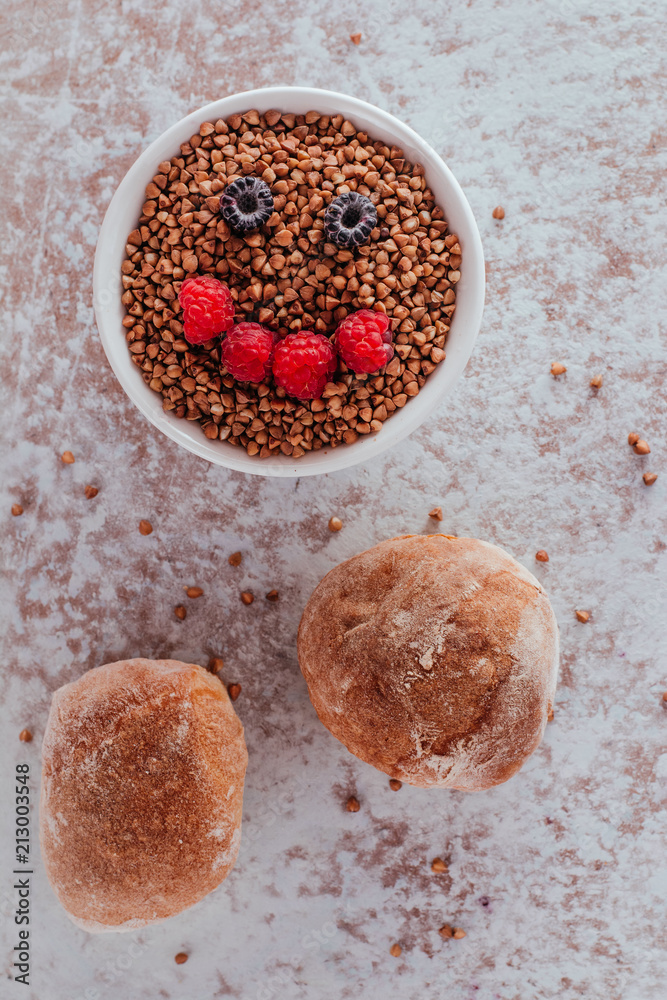 Smile from blackberries and raspberries in a plate with buckwheat and rolls.