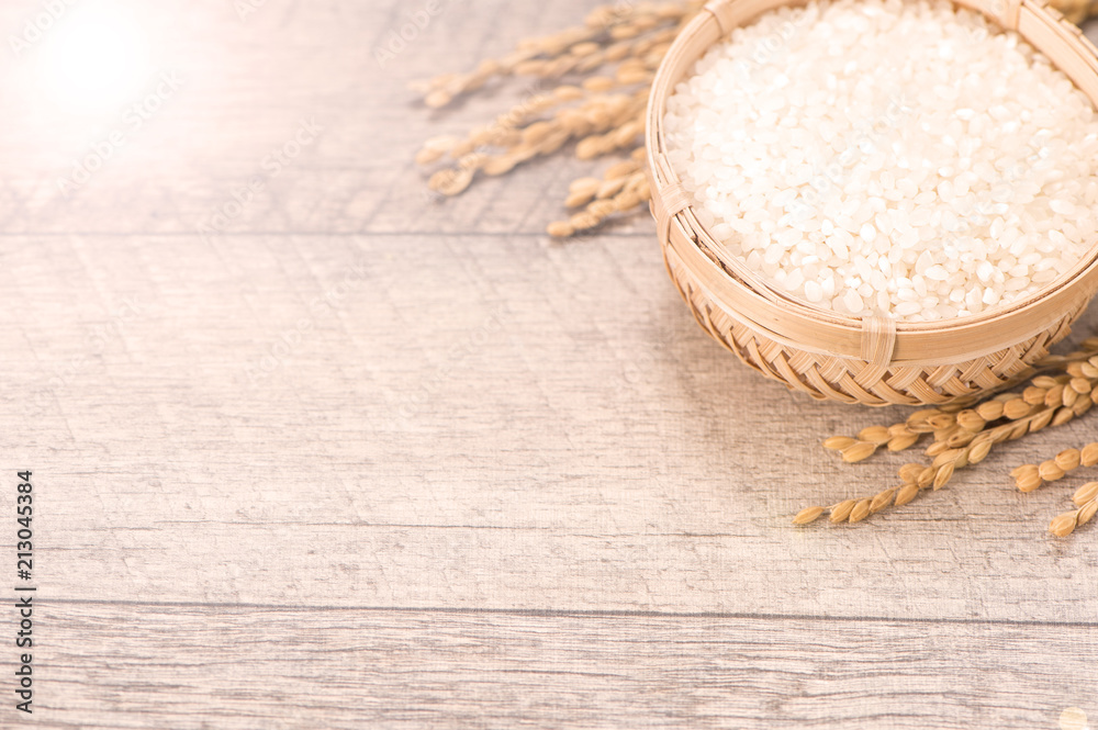 Close up raw rice and unmilled rice in traditions bamboo basket on wooden background, copy space(tex