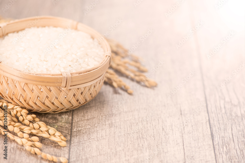 Close up raw rice and unmilled rice in traditions bamboo basket on wooden background, copy space(tex