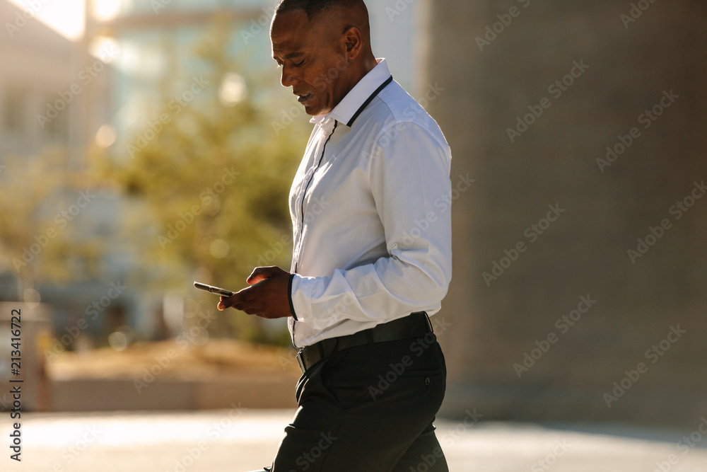 Man using mobile phone while walking on street