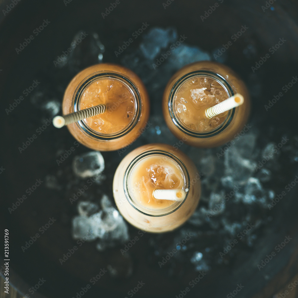 清爽的夏日饮品。装在玻璃瓶里的冷泰国冰茶，深色木棒上放着牛奶