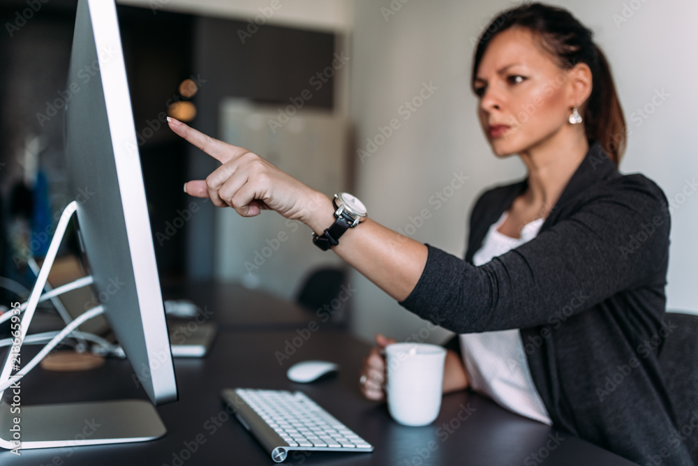 Angry female boss pointing at computer screen.