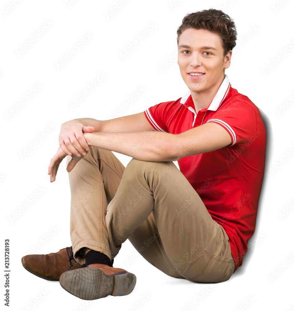 Young man sitting on the ground resting his arms on his leg