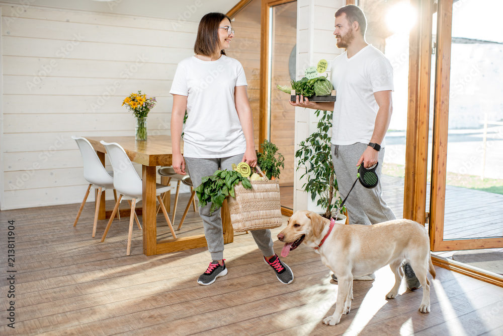 Young couple coming home with dog and fresh green vegetables from the garden or food market