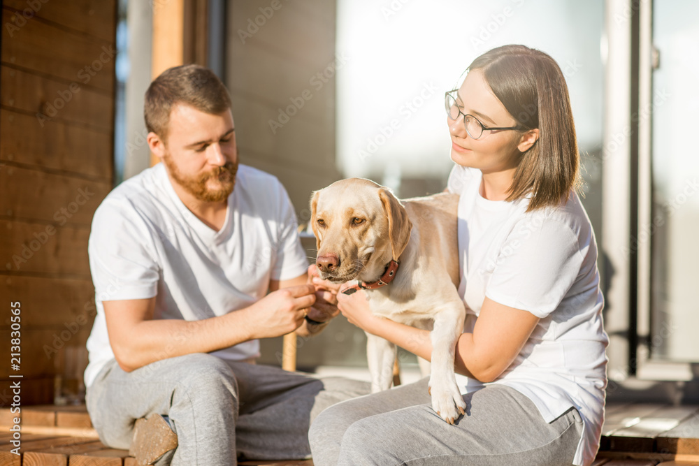 年轻夫妇和他们的幸福狗坐在木屋后院的肖像