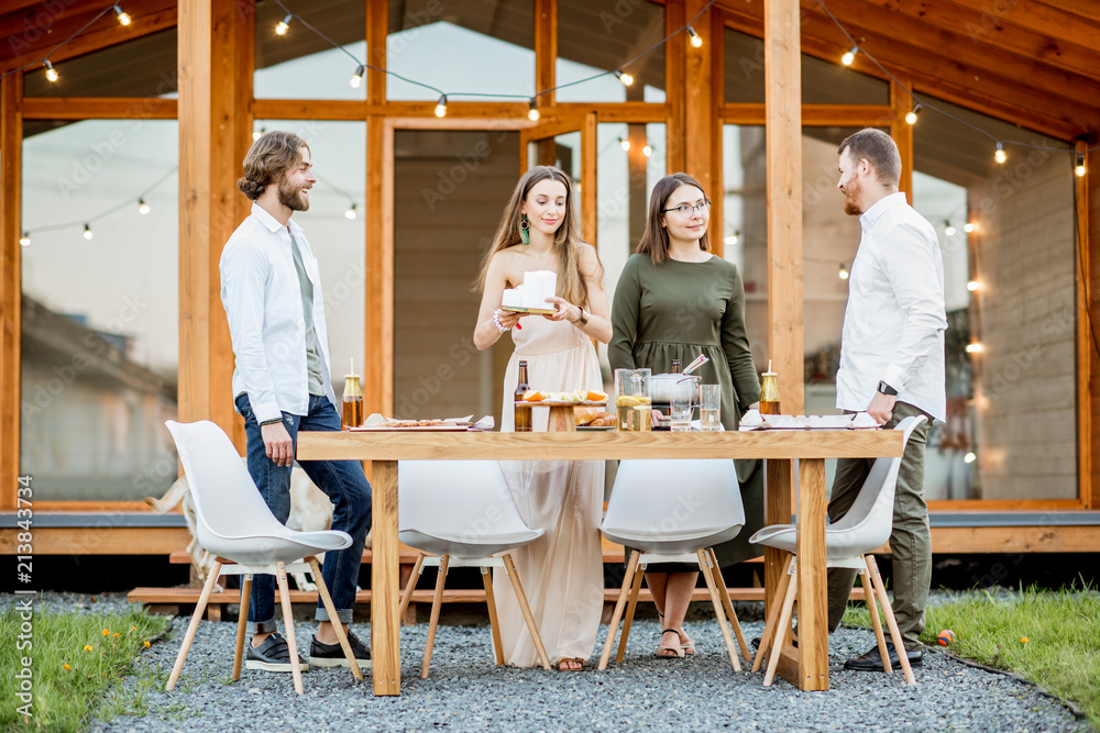 Four friends enjoying evening time together drinking beer on the backyard of the modern country hous