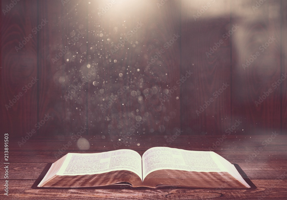 Open old book on wooden table.