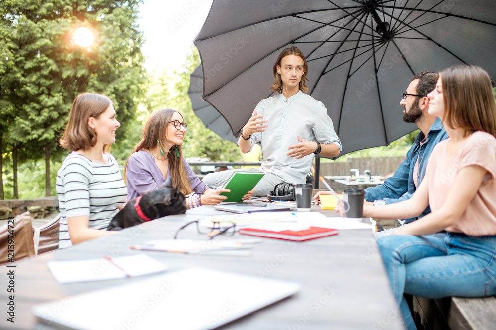 Young friends having fun talking together during a studying outdoors in the park