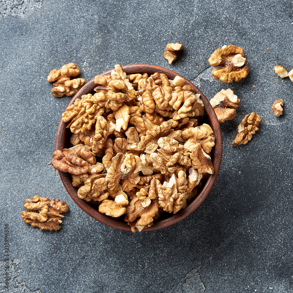 Walnut kernels in a clay bowl on a gray background. Close-up. Top view