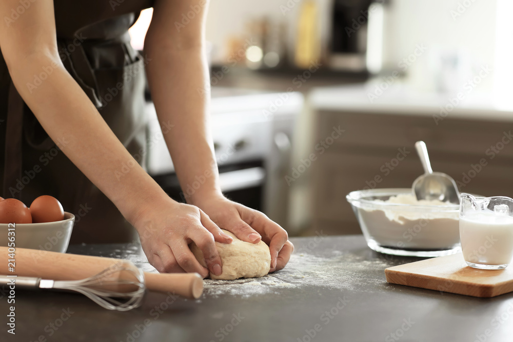 Baker kneading dough on kitchen table