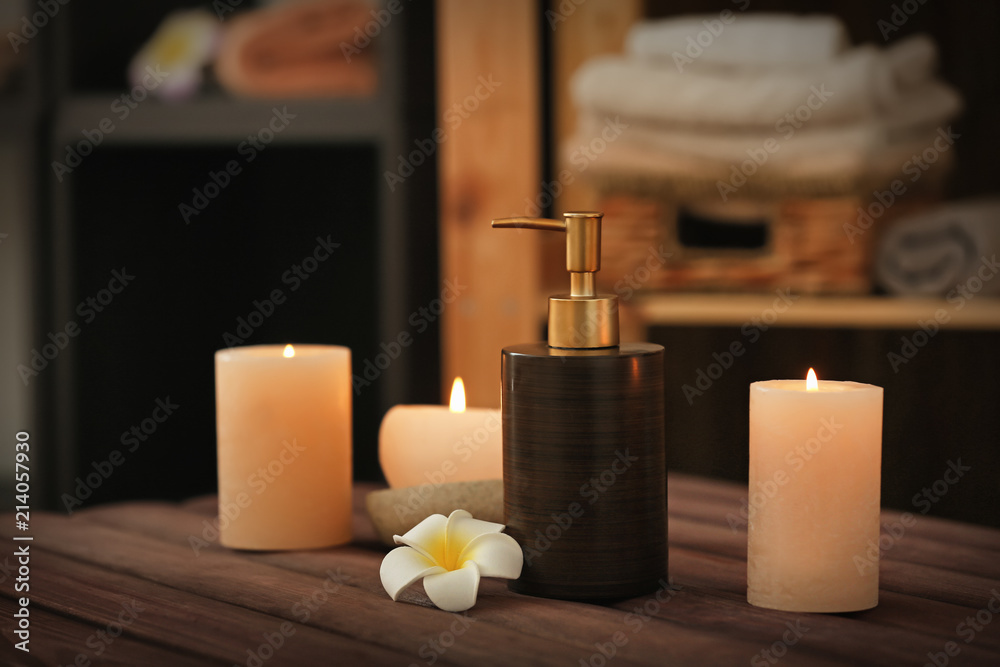 Burning candles and cosmetic product on table in spa salon