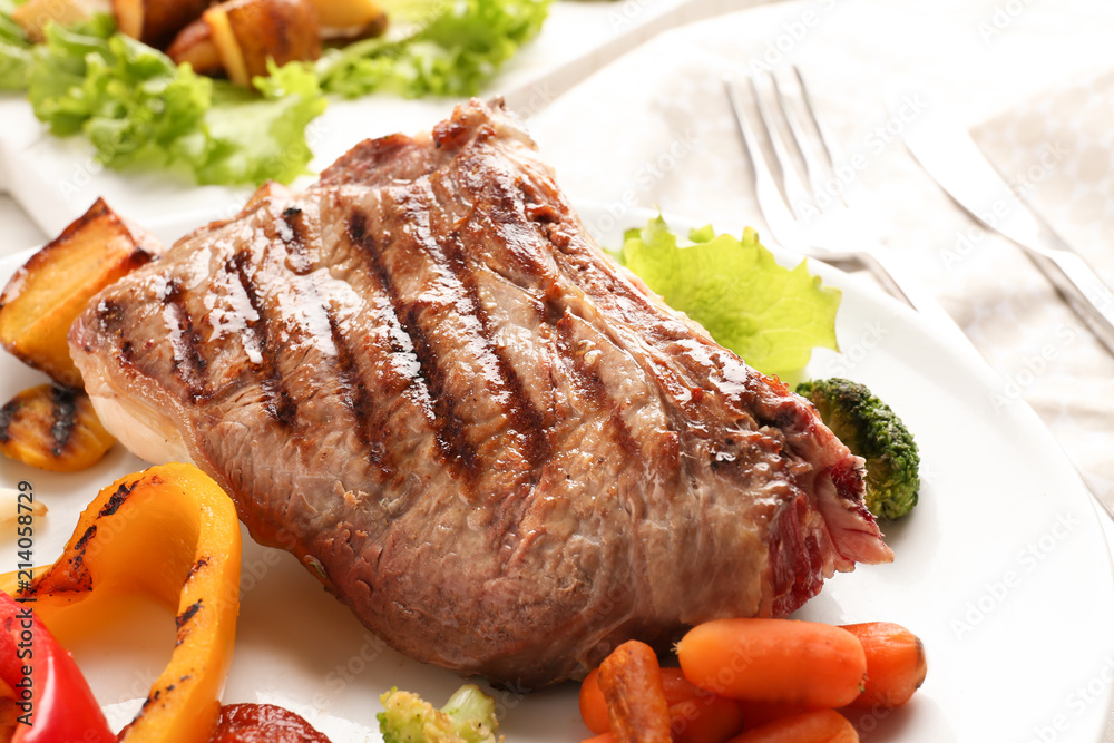 Plate with meat and vegetable garnish on table, closeup