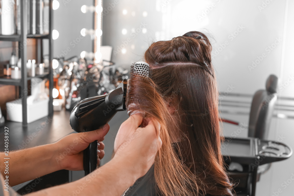 Professional hairdresser working with client in beauty salon