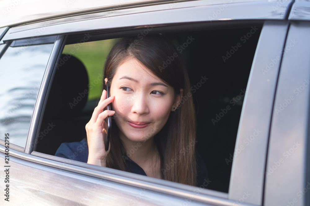 商务女性坐在车上时使用智能手机