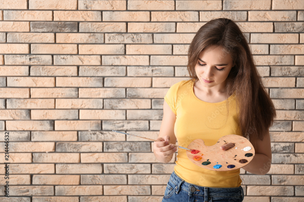 Beautiful female artist against brick wall