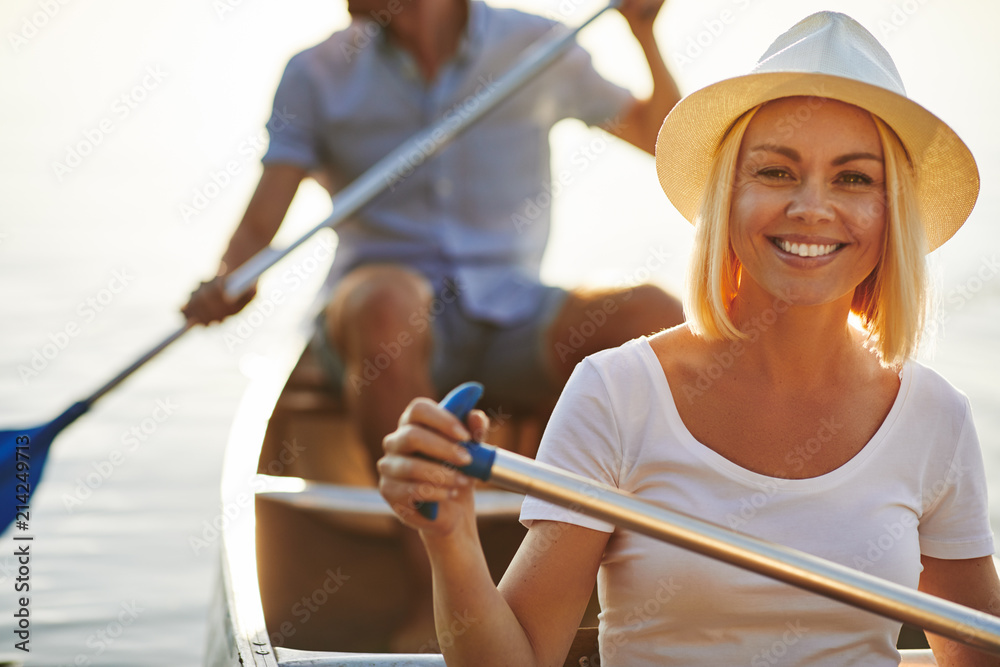 Smiling young woman canoeing with her boyfriend on a lake