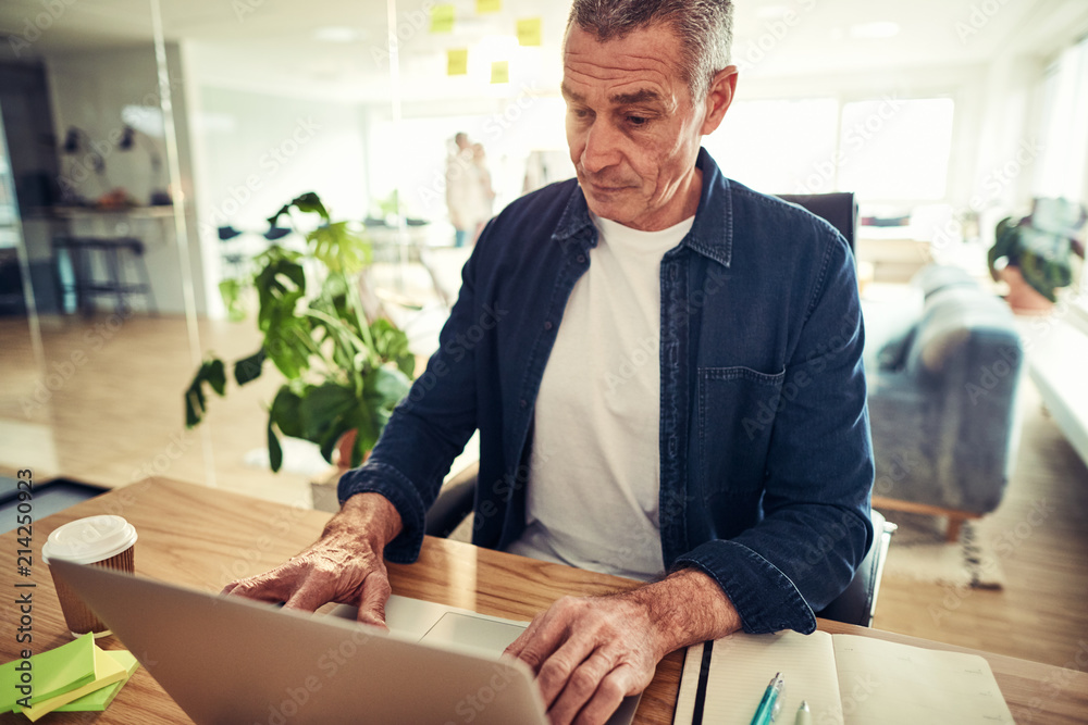 Focused mature businessman working on a laptop in an office