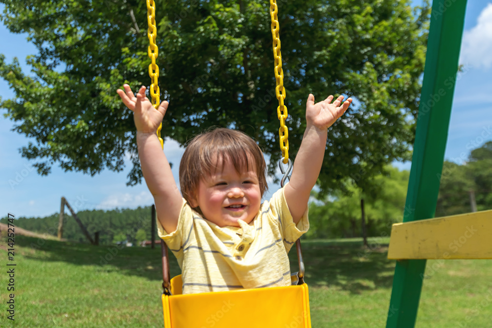 Toddler boy swinging on a swing at a playground