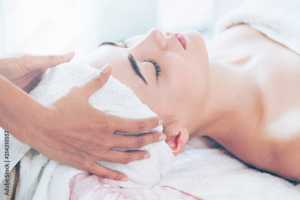 Woman gets facial and head massage in luxury spa.