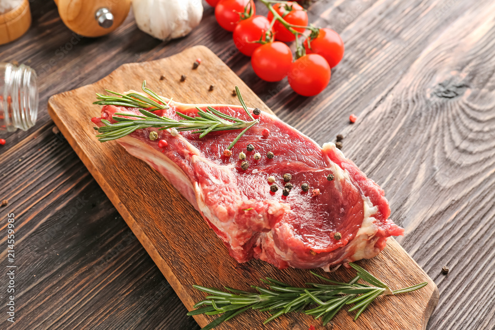 Wooden board with raw meat on table, closeup