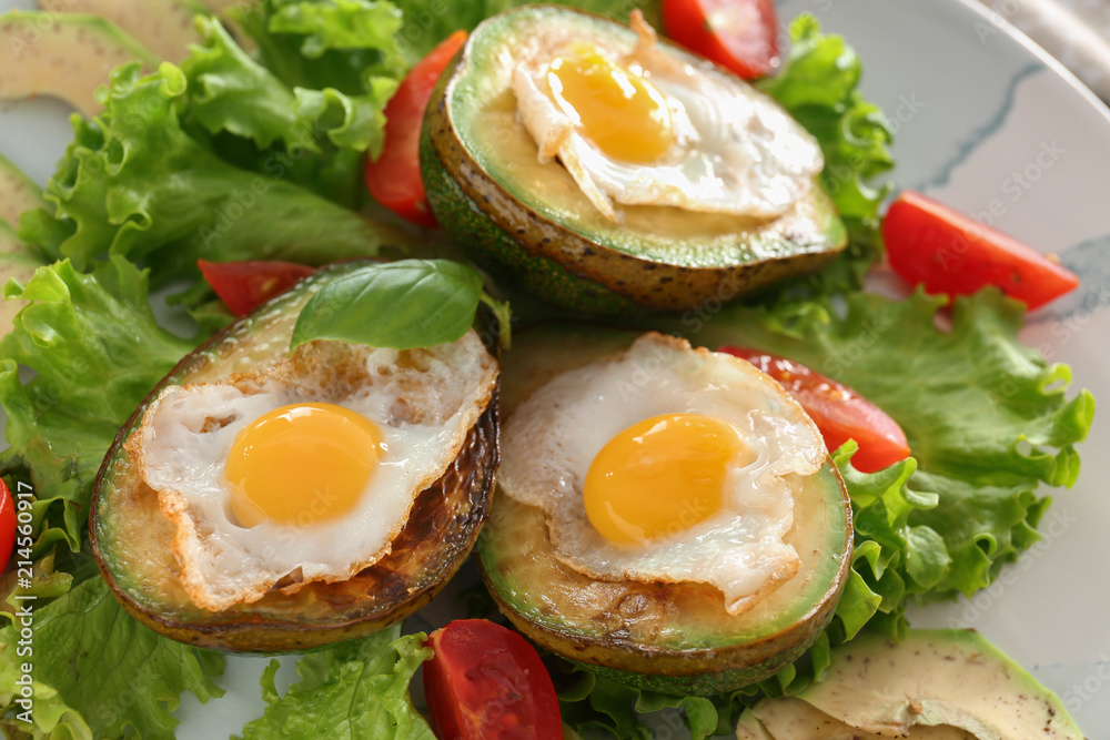 Eggs baked in avocado and fresh vegetables on plate, closeup