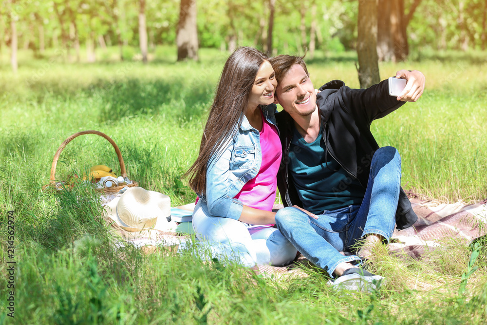 Happy young couple taking selfie in green park