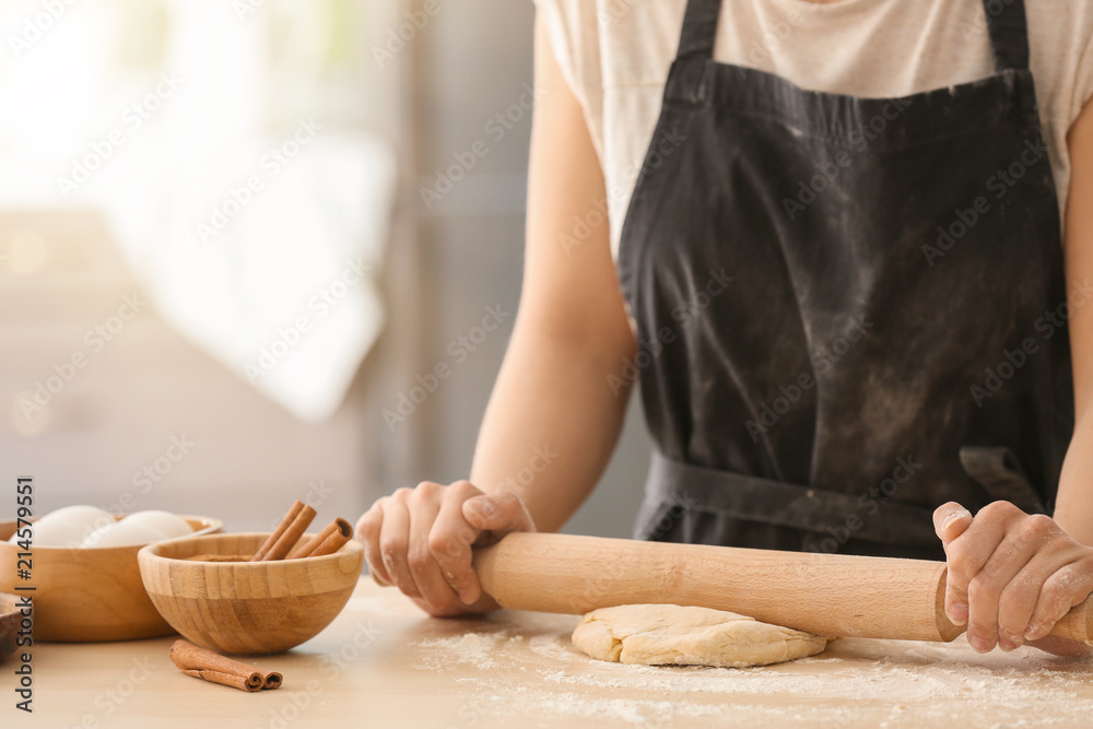 在餐桌上为肉桂面包擀面团的女人