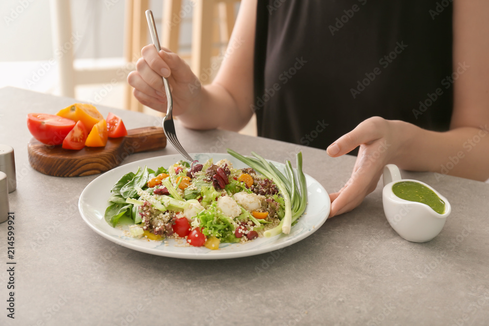 女人在餐桌上吃美味的藜麦沙拉