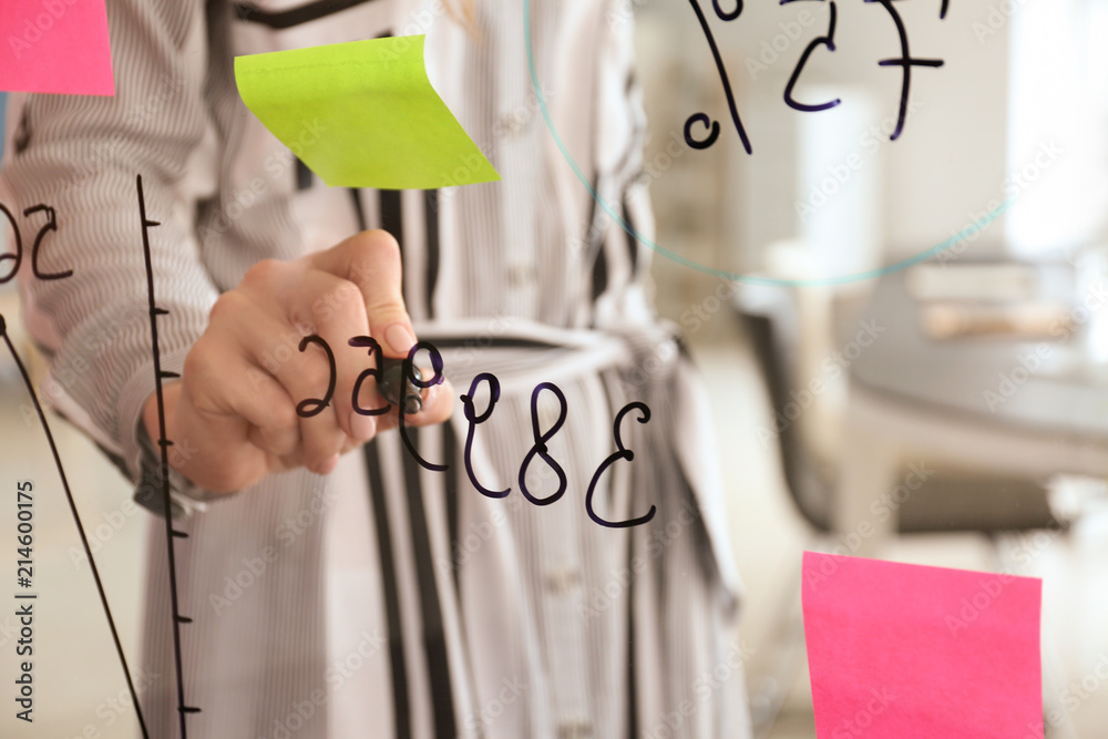 Woman writing on transparent board in conference hall, closeup