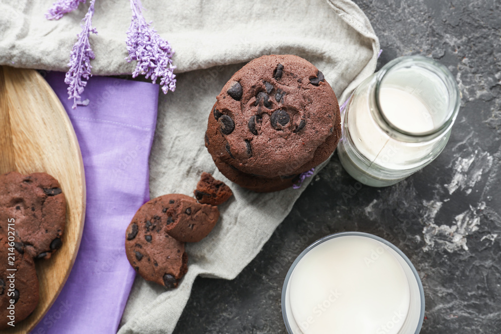 Wooden board with chocolate cookies and milk on table