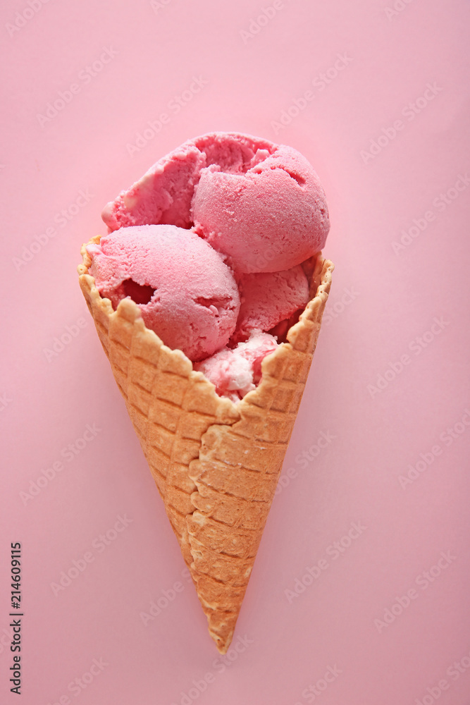 Waffle cone with delicious strawberry ice-cream on color background