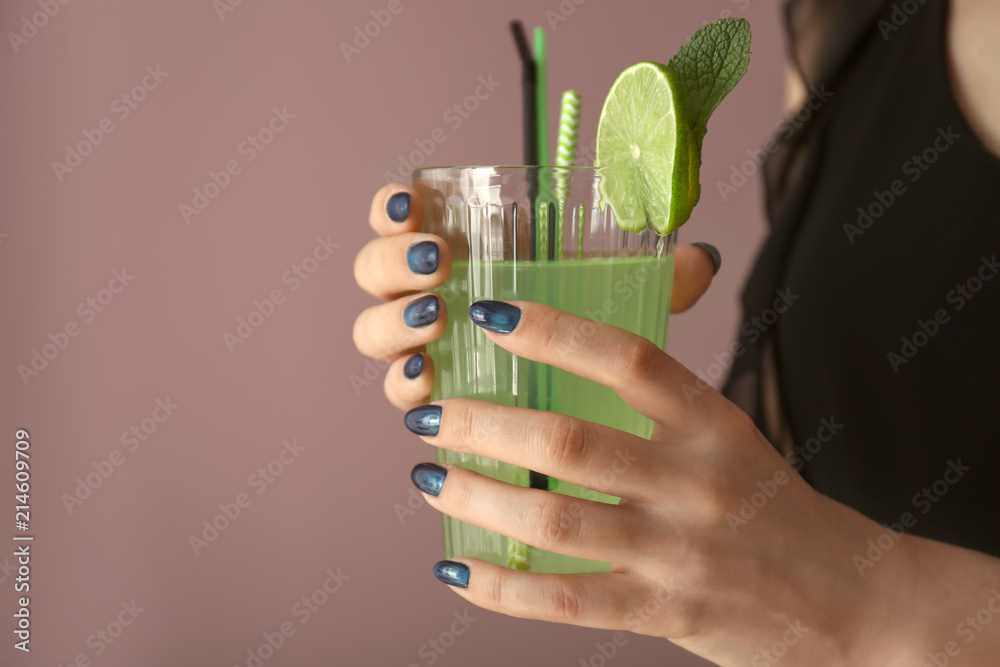 修指甲很漂亮的年轻女人拿着一杯彩色背景的饮料，特写镜头