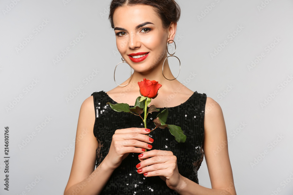 Young woman with beautiful manicure and flower on grey background