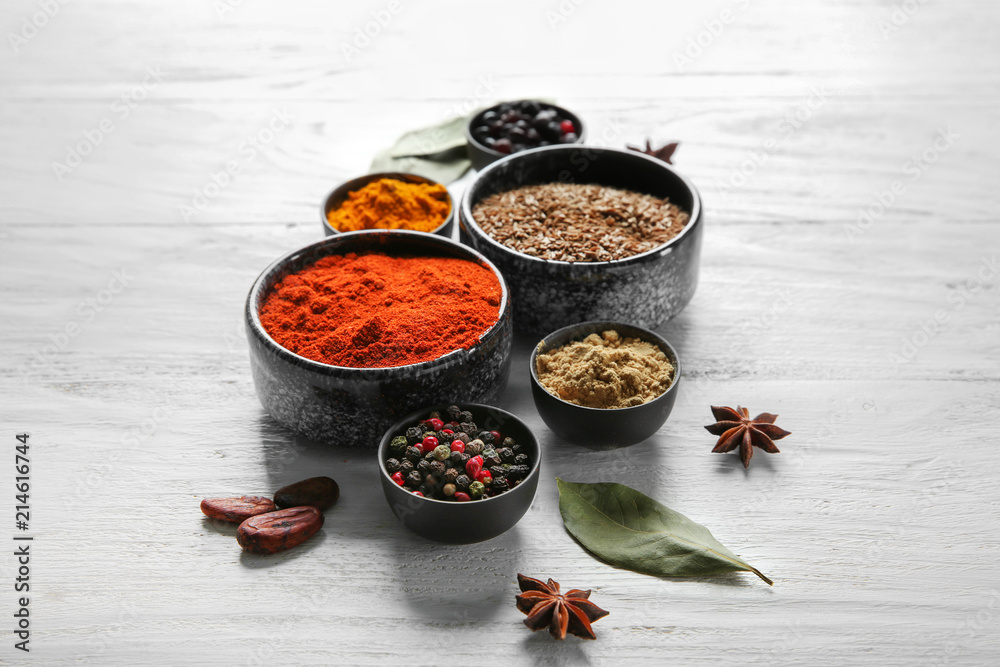 Bowls with different dry spices on wooden background