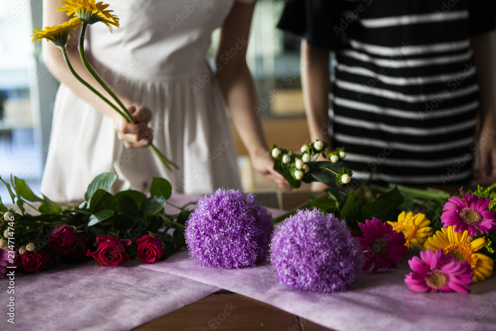 机に花を並べ綺麗な花束を作る女性二人