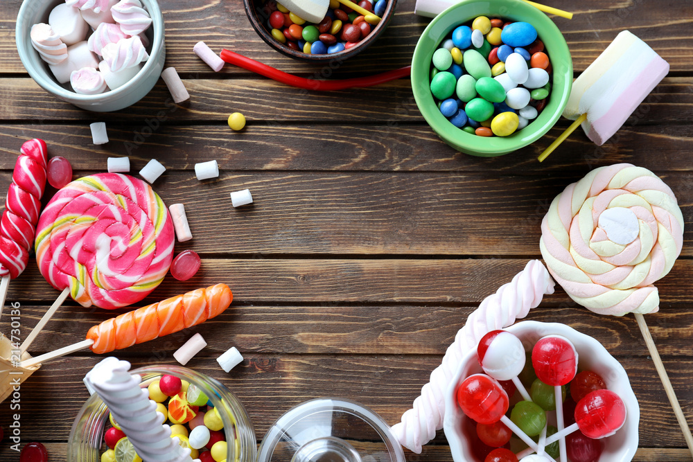 Frame made of colorful candies, lollipops and marshmallows on  wooden background