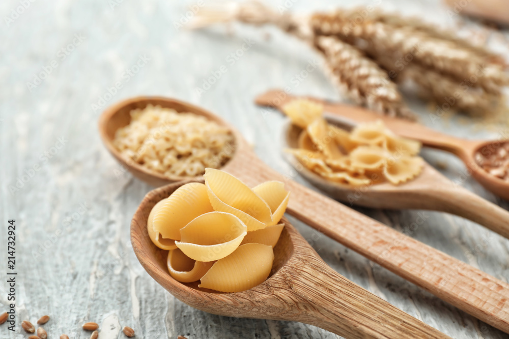 Spoon with wheat pasta on wooden table