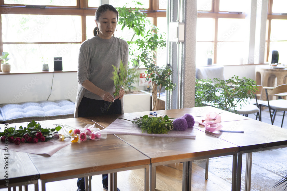 お客様にお渡しする花束を真剣に丁寧に作り上げる女性店員