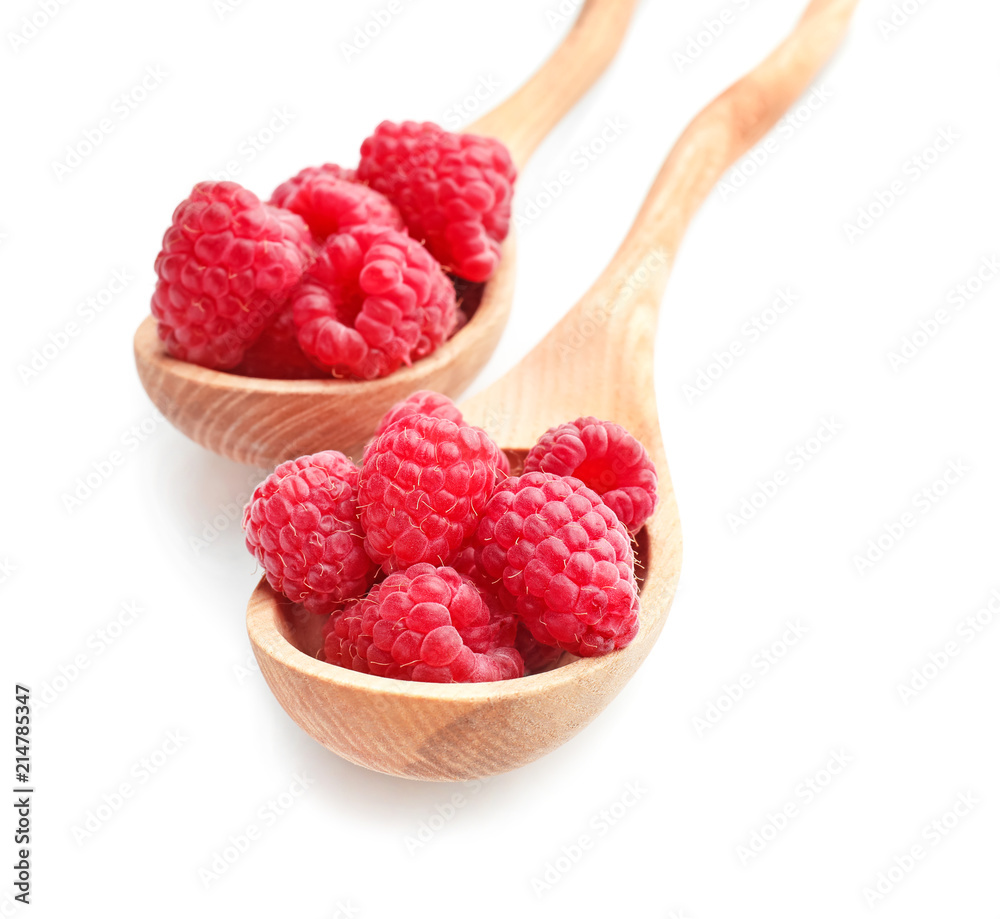 Wooden spoons with sweet ripe raspberries on white background