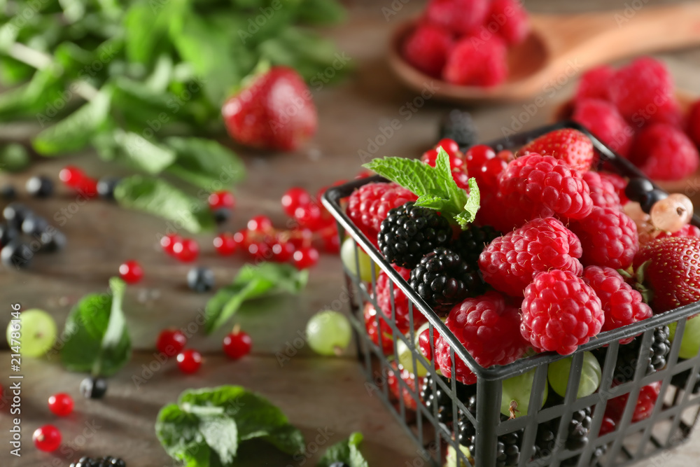 Basket with delicious berries on wooden background